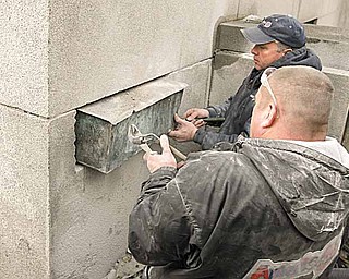 Steve Kibbler, left, and Bob Harris, also of Ameriseal, remove the time capsule, which was encased during a cornerstone-laying ceremony June 11, 1908. The courthouse opened three years later.