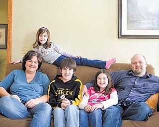 Dan and Lorie Barber of New Middletown risked fetal surgery to repair the spine of their daughter, Nicole, in hopes of lessening the effects of her spina bifida. The Barber family, from left, Lorie, Nicole (lying across the back of the sofa); Zack, 12; Taylor, 10; and Dan. Nicole is a good reader and speller and last year ran the 50-yard dash in the Junior Olympics at her school.