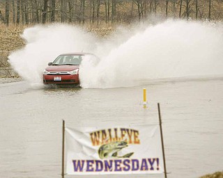 SURFS UP and Walleye Wednesday can't be far behind as a motorist blows through the water covering the road by Drakes Landing on Western Reserve Road.