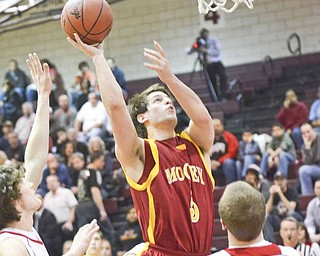 Cardinal Mooney’s Kevin McGuire (5) scores over Crestwood’s Clay Walters (23) during a Division II tournament basketball game Wednesday at Boardman High School. The Cardinals held on to defeat the Red Devils, 61-55.