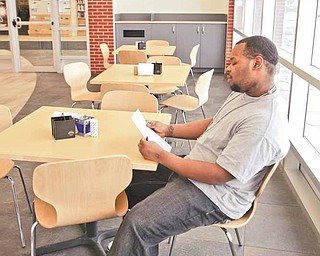 D'Andre Damous checks out a menu at the cafe - Inside the Newport Branch of the Younstown Public Library is a corner cafe that one would see in New York. New Seasonings at Chapters is operated by Everlife Worship Center from the Eastside of Youngstown and offers everything from coffee to salads soups and sandwiches.