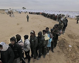 Men from Bangladesh, who used to work in Libya and fled the unrest in the country, wait in line for food in a refugee camp at the Tunisia-Libyan border, in Ras Ajdir, Tunisia, Tuesday March 8, 2011. The 20,000-capacity transit camp for thousands of migrant workers who have fled the fighting in Libya in the past two weeks is about seven kilometers (four miles) from the Libyan border and is expanding with each day of crisis in Libya.