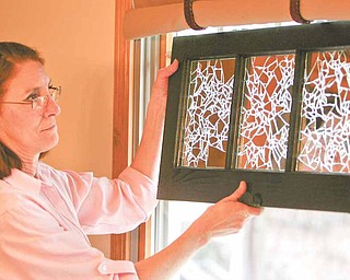 Unusual patterns are highlighted as light from a window flows through a finished window pane that Dru Marchese of Poland decorated with shards of mirror glass. Marchese, diagnosed with multiple sclerosis in 1998, will display her work Saturday as part of an MS Awareness Month art show and auction in Akron.