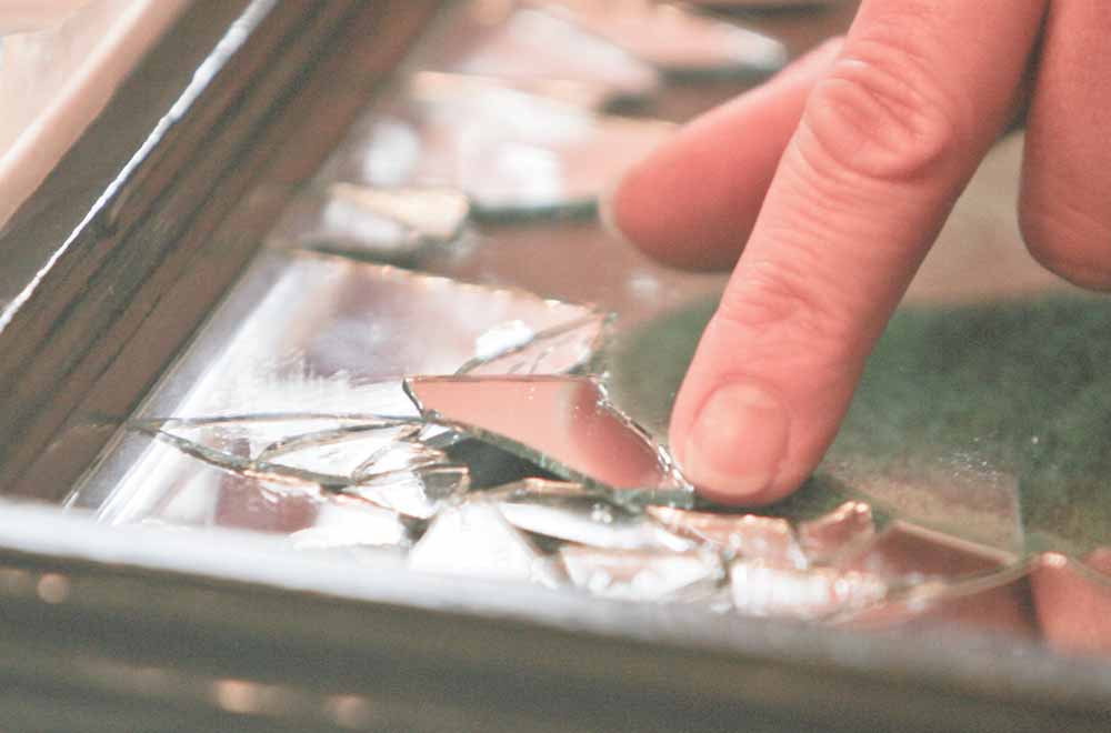 Dru Marchese carefully places one of the broken mirror pieces onto a window pane. 