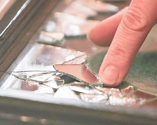 Dru Marchese carefully places one of the broken mirror pieces onto a window pane.