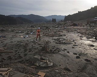 A Japanese rescue team member walks through the completely leveled village of Saito in northeastern Japan Monday, March 14, 2011. Rescue workers used chain saws and hand picks Monday to dig out bodies in Japan's devastated coastal towns, as Asia's richest nation faced a mounting humanitarian, nuclear and economic crisis in the aftermath of a massive earthquake and tsunami that likely killed thousands.