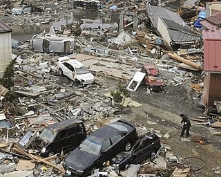 People carry the body of a victim through debris in Kesennuma, Miyagi, northern Japan Tuesday, March 15, 2011 following Friday's massive earthquake and the ensuing tsunami. 