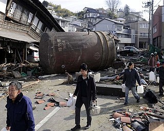 People walk to receive water supply through a street with the rubble Monday March 14, 2011 in Kesennuma, Miyagi Prefecture, northern Japan following Friday's massive earthquake and the ensuing tsunami. 