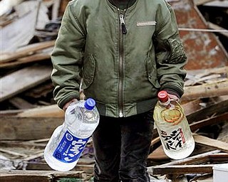 Boy carries bottles of water amid debris in Kesennuma, northern Japan Monday, March 14, 2011 following Friday's massive earthquake and the ensuing tsunami. 