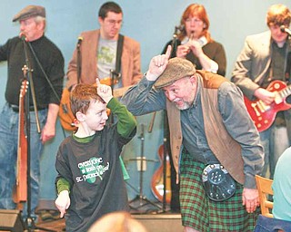Kicking off St. Patrick’s Day with the traditional unicorn song are William D. Lewis, right, and Michael Morgan, 6, of Liberty, the son of Jim and Kara Morgan. Lewis, a veteran Vindicator photographer, is part of County Mayo, an Irish band that played Wednesday for customers at Kravitz Deli in Liberty.