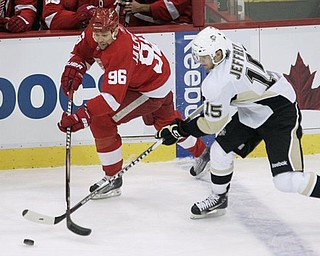 Detroit Red Wings' Tomas Holmstrom (96), of Switzerland, and Pittsburgh Penguins' Dustin Jeffrey (15) reach for the puck in the first period of an NHL hockey game Monday, March 21, 2011, in Detroit.