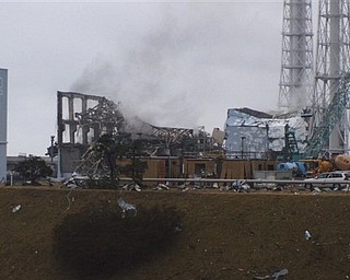 In this photo released by Tokyo Electric Power Co. (TEPCO), gray smoke rises from Unit 3 of the tsunami-stricken Fukushima Dai-ichi nuclear power plant in Okumamachi, Fukushima Prefecture, Japan, Monday, March 21, 2011. Official says the TEPCO temporarily evacuated its workers from the site. At left is Unit 2 and at right is Unit 4.