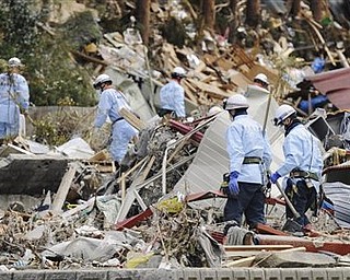Search and rescue team members look for survivors at Minamisanrikucho, northeastern Japan, Tuesday, March 22, 2011, after the March 11 earthquake and resulting tsunami that hit the country’s northeast coast. 