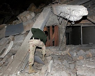 A Libyan soldier surveys the damage to an administrative building hit by a missile late Sunday, March 20, 2011 in the heart of Moammar Gadhafi's Bab Al Azizia compound in Tripoli, Libya, as he is pictured during an organized trip by the Libyan authorities. No casualties were reported.