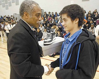 Jerome Harrell, left, principal of Wilson Middle School, Youngstown, presents a pair of shoes to eighth-grader Jonathon Flores. The shoes were presented Wednesday to several students by the family members of Jamail Johnson, who was killed Feb. 6 at a shooting a home near Youngstown State University. Johnson, 25, a YSU student had served as a mentor at the school.
