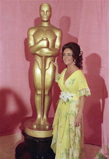 This April 2, 1974 file photo shows actress Elizabeth Taylor standing by a statue of the Academy Award Oscar in Los Angeles.  Elizabeth Taylor had it all: the violet, almond-shaped eyes, the creamy skin, the pouty lips and raven hair. Of course, there were her Oscars, iconic roles and many husbands, too, but Taylor is indeed most renowned for her beauty. She died Wednesday at age 79 of congestive heart failure. 