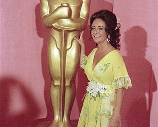 This April 2, 1974 file photo shows actress Elizabeth Taylor standing by a statue of the Academy Award Oscar in Los Angeles. Elizabeth Taylor had it all: the violet, almond-shaped eyes, the creamy skin, the pouty lips and raven hair. Of course, there were her Oscars, iconic roles and many husbands, too, but Taylor is indeed most renowned for her beauty. She died Wednesday at age 79 of congestive heart failure.