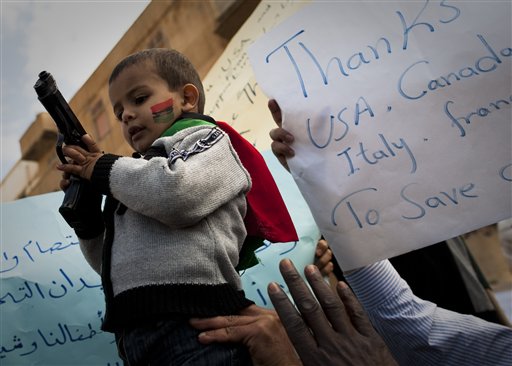 A gun was handed over to a Libyan boy during a rally in support  of the allied air campaigns against the troops of Moammar Gadhafi in Benghazi, eastern Libya, Wednesday, March 23, 2011. 