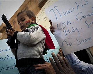 A gun was handed over to a Libyan boy during a rally in support of the allied air campaigns against the troops of Moammar Gadhafi in Benghazi, eastern Libya, Wednesday, March 23, 2011.
