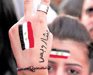 Pro-Syrian President Bashar Assad protester, flashes V sign as she painted on her hand Syrian flag with Arabic words read:" Only Bashar," in Damascus, Syria, on Saturday March 26, 2011. Protesters set fire to offices of the ruling party in southern and western Syria on Saturday, burning tires and attacking cars and shops in a religiously mixed city on the Mediterranean coast, according to accounts by government officials, activists and witnesses.