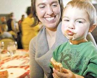 David Fielding, 2, of Hudson, chows down on a slice of pizza during The Mahoning Valley Pizza Cook-Off on Sunday at Mr. Anthony’s in Boardman. Looking on is David’s mother, Audrey Fielding. They were among more than 1,000 who attended the event, a fundraiser for The Potential Development Program/School of Autism agency.