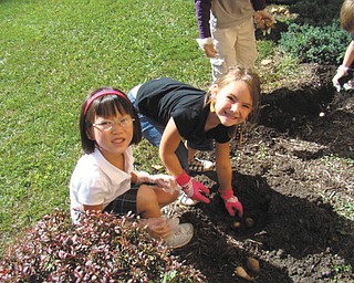 Jia Li Dugan, left, and Nicollete Leonard of Mrs. Bond's kindergarten class at St. Patrick School in Hubbard plant spring bulbs in front of the school. Photo sent in by Roberta Robinson.