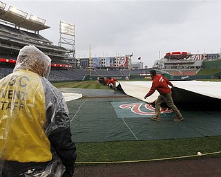Workers cover the field as Washington Nationals practice is halted at Nationals Park on Wednesday, March 30, 2011, in Washington. The Nationals home-opener is scheduled for Thursday against the Atlanta Braves.