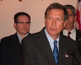 Gov. John Kasich talks to reporters before signing into law legislation requiring performance audits of certain state agencies. Public Utilities Commission Chairman Todd Snitchler is looking on in the background.