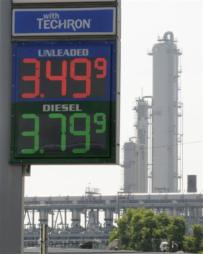 In this March 30, 2011 file photo, a Houston gas station displays its prices with a refinery stack in the background. Quick: What do these things have in common? Libyan leader Moammar Gadhafi. The Japanese earthquake and tsunami. Wall Street volatility. A cranky, even angry American populace. Answer: They all have something to do with gasoline. No matter what happens in the world today, just about everything seems to point back to fuel and the tricky politics that emerge when prices spike. 