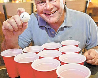 Chuck Zarbaugh shows off his beer-pong gear at Buffalo Wild Wings restaurant in Boardman. Zarbaugh created the Mahoning Valley Beer Pong League, which he said will begin in May. Zarbaugh’s version of the game substitutes water for beer to attract young people to the sport.