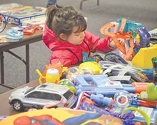 Lila Wade, 3, of Austintown inspects a table of toys at the Trash and Treasure Sale at Austintown Senior Center on Saturday afternoon. Funds raised at the event help keep the center running.