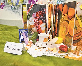 Sue Lambert ties in a display of a teacup, scone, fruit and teabags for tea time with the book “Afternoon Tea” in the Altered Book Art Gallery.