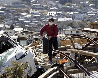 A survivor Keichi Kudo picks up car tire near the his damaged house at a devastated area in Ofunato, Iwate Prefecture, Japan, Wednesday, April 6, 2011, following the March 11 earthquake and tsunami.