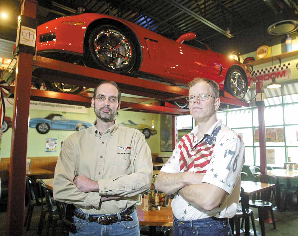 Dave Millich, left, president of the Mahoning Valley Corvettes club, stands near his 2010 Corvette Grand Sport on display at Quaker Steak & Lube in Austintown. His 1984 Fitch High School classmate Rob Bowman, right, has a 1967 Chevy Chevelle on display at the restaurant.