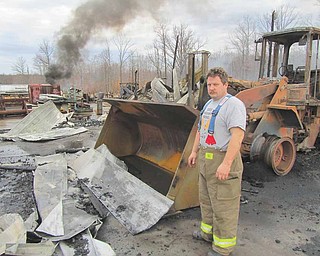 Todd Garland, Warren Township fi re chief, stands in front of one of two front loaders that were ruined at Doll Lumber, 1363 state Route 534 in Braceville Township, early Monday during a fire that destroyed a storage building and all of its contents.