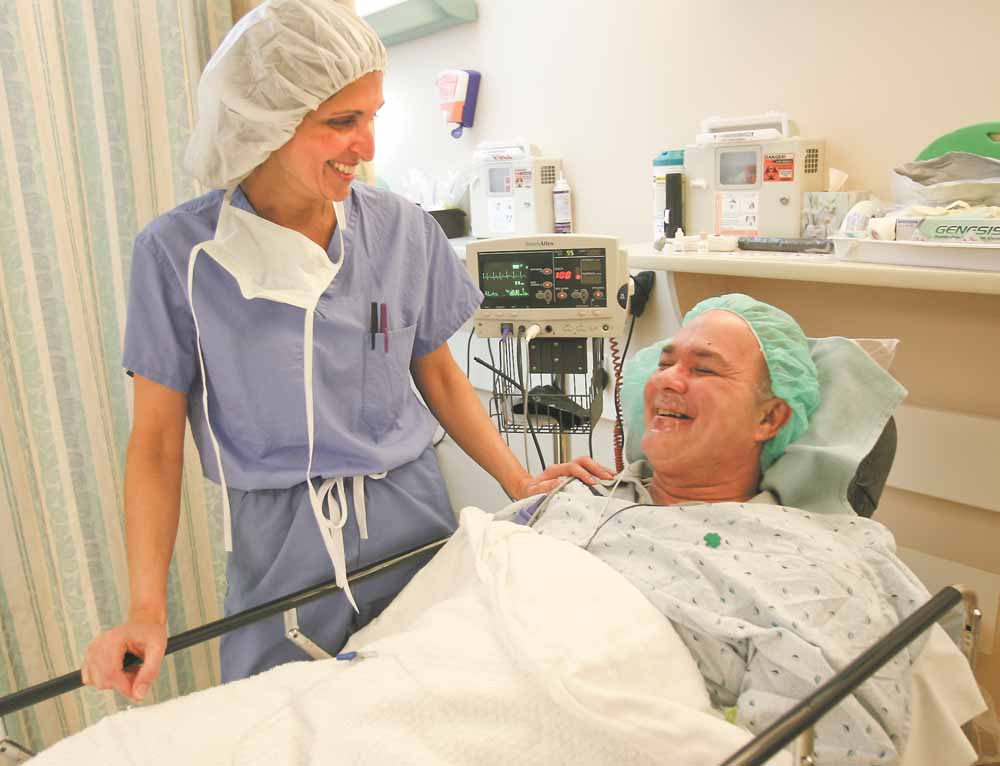 Dr. Sergul Erzurum, left, of Eye Care Associates, talks with cataract patient Ronald Zingaro of Boardman before surgery. One day a year, Eye Care Associates surgeons provide free cataract surgery to people who don’t have health insurance or other means of paying for the operation.