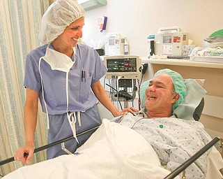Dr. Sergul Erzurum, left, of Eye Care Associates, talks with cataract patient Ronald Zingaro of Boardman before surgery. One day a year, Eye Care Associates surgeons provide free cataract surgery to people who don’t have health insurance or other means of paying for the operation.
