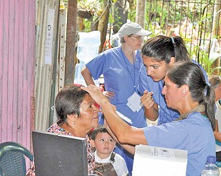 Dr. Sergul Erzurum, right, examines a patient during a MedWish International medical mission to El Salvador. Looking on at the doctor’s right is her daughter, Aylin, 16.