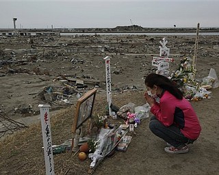 A survivor pray in an area destroyed by tsunami in Natori, Miyagi Prefecture, northern Japan, Monday, April 11, 2011, one month to the day after an earthquake and tsunami devastated the city.