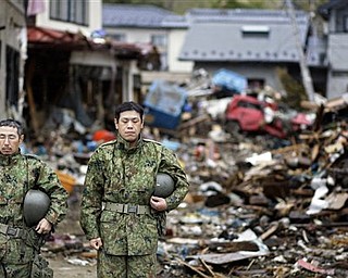 Members of Japanese Self-Defense Force stop for a moment of silence at 2:46pm, exactly a month after a massive earthquake struck the area in the port town of Kesennuma, Miyagi Prefecture, Japan, Monday, April 11, 2011.