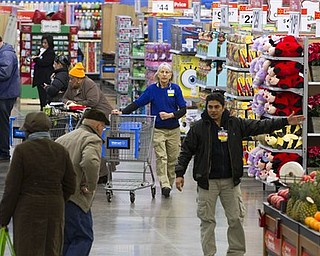 In this file photo taken Dec. 15, 2010, an employee directs a customer inside a Wal-Mart store in Alexandria, Va. Wal-Mart Stores Inc. is launching a national TV ad campaign Monday, April 11, 2011, highlighting its renewed focus on low prices and its price match policy in a bid to bring back customers who no longer trust it has the lowest prices.