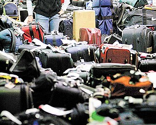 In this Feb. 20, 2007 file photo, Carolann Manfredi, of Princeton, N.J., searches through luggage for a bag she says has been missing for five days, at the Philadelphia International Airport. The Department of Transportation is proposing a new rule, in 2011, requiring automatic refunds for delayed luggage. The major airlines, which are collecting more than $3.3 billion in bag fees a year, are opposed. (AP Photo/Matt Rourke, file)