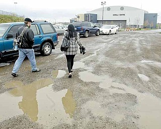 Dave Goettsch and Makeda Mosley, who both work for VXI Global Solutions, try not to get muddy as they walk to work from a free parking lot at the Covelli Centre in downtown Youngstown.