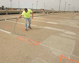 Ron Williams of SMCI Construction checks and marks the upper deck of the M2 Lincoln Avenue parking deck at Youngstown State University. The places being marked will be dug up and replaced. The deck will close Monday through Aug. 29 for repairs.