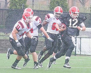 Kurt Hess (12), starting quarterback for the Red team, sprints down the field past White defenders Ali Cheaib (51),  Thomas Sprague (34) and Obinna Ekweremuba (90) during the Youngstown State football team’s annual spring game Saturday at YSU’s Stambaugh Stadium. Hess completed 11 of 19 passes for 139 yards and one touchdown, but the Red team was defeated by the White, 24-14. 
