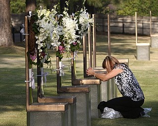 Regina Bonny, a retired Midwest City, Okla., police officer from Moore, Okla., kneels at the chair of DEA agent Kenneth Glenn McCullough in the field of chairs at the Oklahoma City National Memorial and Museum in Oklahoma City, Tuesday, April 19, 2011, on the 16th anniversary of the Oklahoma City bombing.