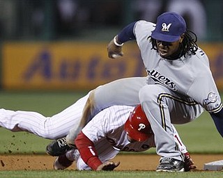 Philadelphia Phillies' Carlos Ruiz rolls under Milwaukee Brewers second baseman Rickie Weeks during the fourth inning of a baseball game Tuesday, April 19, 2011, in Philadelphia. Ruiz was out at second on a ball hit by Wilson Valdez.