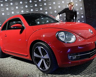 A man cleans the new Beetle car by the German car company Volkswagen after a news conference in Berlin Monday, April 18, 2011. In its 73-year history, the Beetle has evolved from the hippie ride of choice to a cute chick car. Now Volkswagen is reinventing it again. 