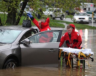 Green Twp. Fire firefighter/paramedic Don Patterson, left, and Lt. Arlis Boggs, right, rescue a woman  from her car, which was stuck in high water on Tuesday, April 19, 2011 in Green Twp., Ohio. Water from a lake behind the houses, combined with with clogged sewer drains caused the water to reach her doors. The woman was uninjured, but rescue personnel used a stretcher to transport her to dry ground.