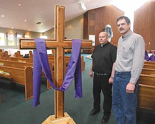 The Rev. Stephen Popovich, pastor of St. Paul the Apostle Church in New Middletown, and Russ Ohlin, a church member, stand next to the handmade cross and base that Ohlin crafted. The cross, which has been on display during Lent, will be carried in a Good Friday service at 7 p.m. today. 
